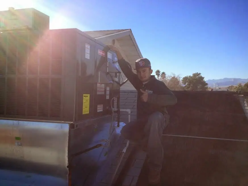 HVAC technician performing Air Duct Repair on a rooftop unit in North Valley